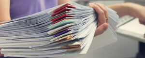 Womans hand holding stack of documents in purple shirt